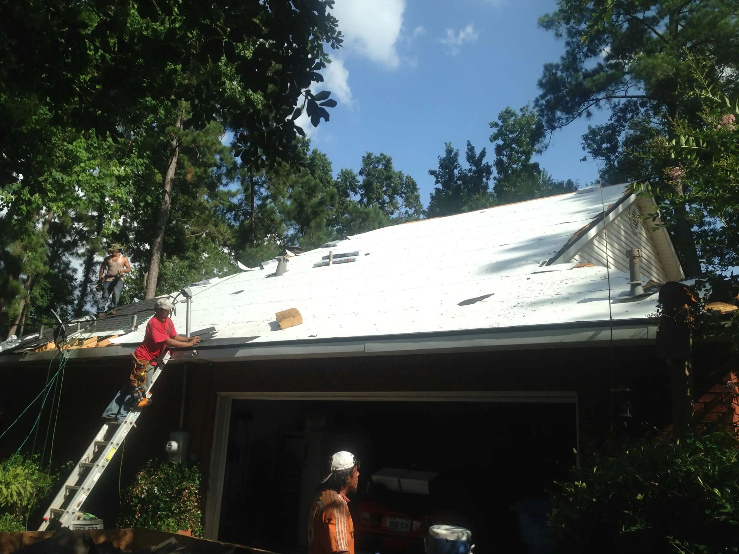 Roofer on a ladder installing underlayment on a roof deck